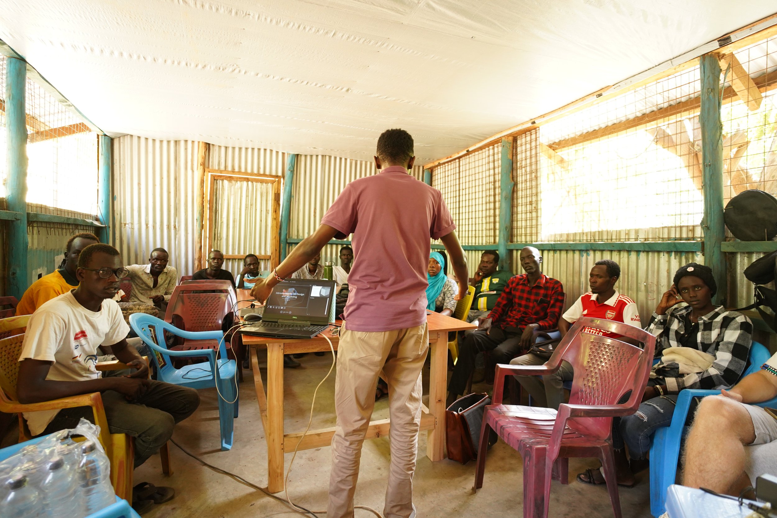 youth in Kakuma refugee camp gathered in a group learning 3d modelling in a classroom